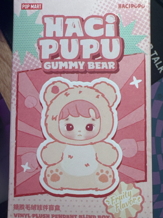 HACIPUPU is a gentle, big-eyed character created by POP MART and known for his cozy bear suit and sweet, whimsical aesthetic, who has been featured in various collectibles like plush figures and blind boxes